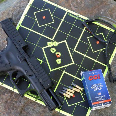 A handgun, glasses and CCI ammo laying on top of a shot target.