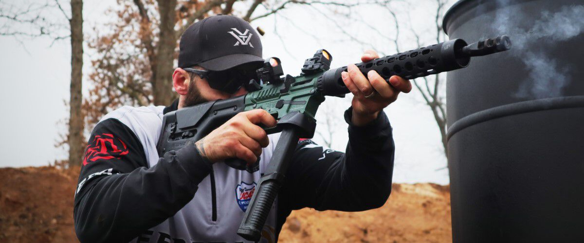 Josh Froelich Shooting A Rifle around a barrel