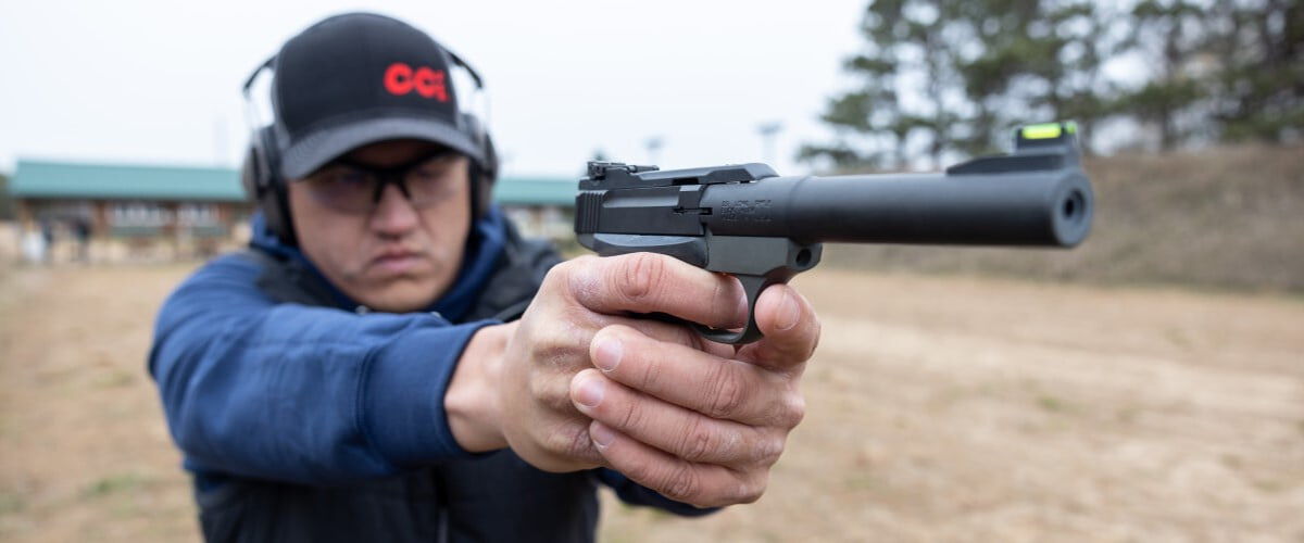 shooter aiming a handgun at an outdoor range