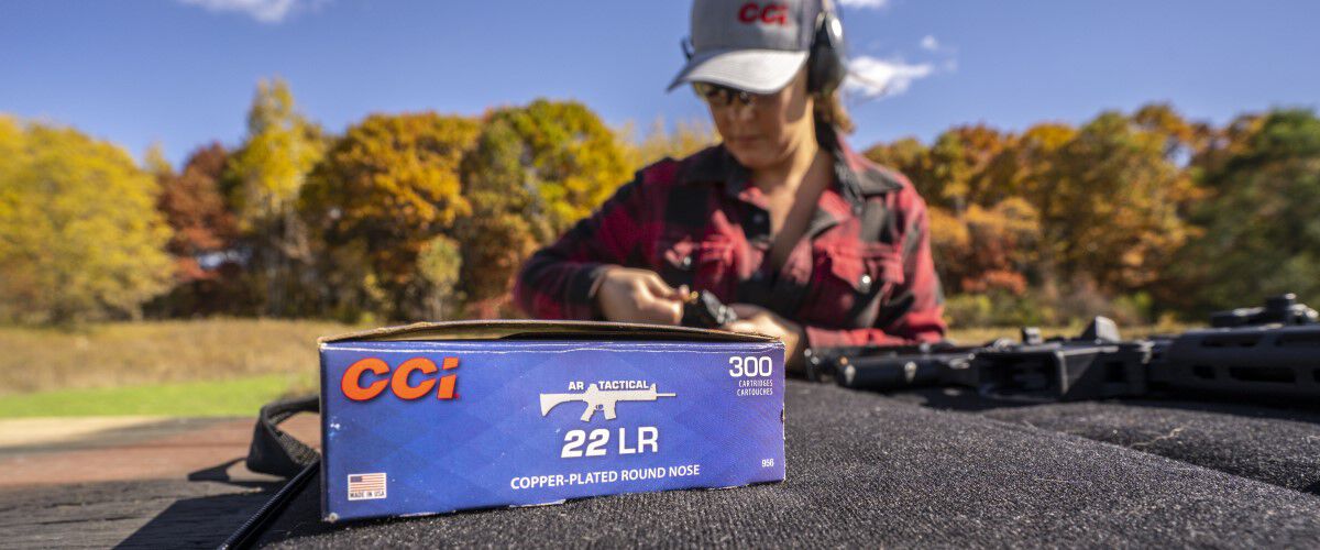 female shooter loadding a magazine with a box of 22 LR sitting in the foreground.