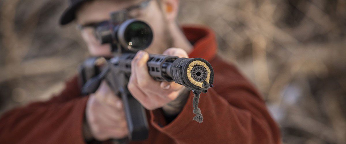 shooter aiming rifle with suppressor