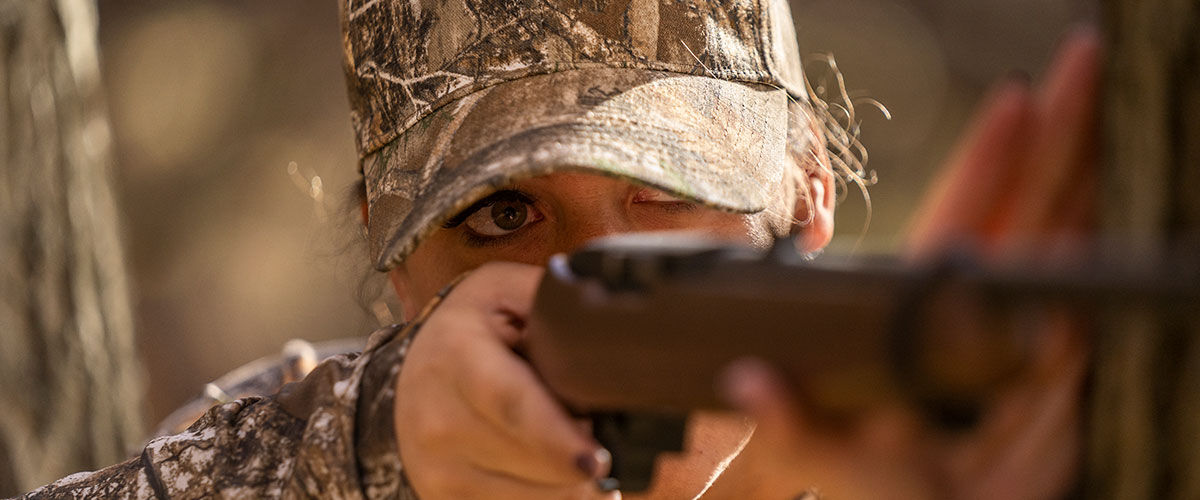 Woman shooting rimfire rifle in the field