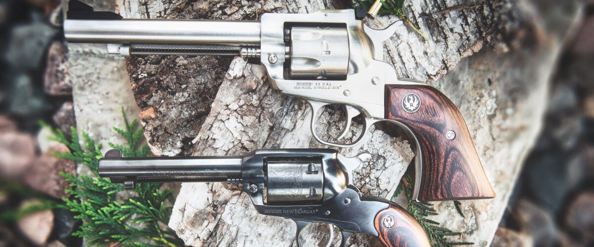 Two handgun laying one above the other on a tree stump