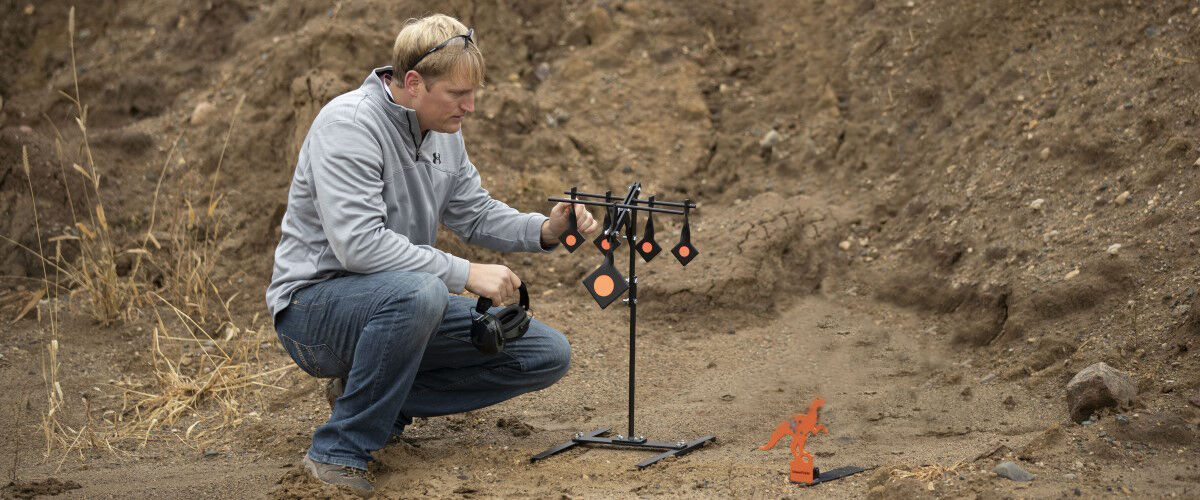 Guy setting up metal target in front of a side embankment