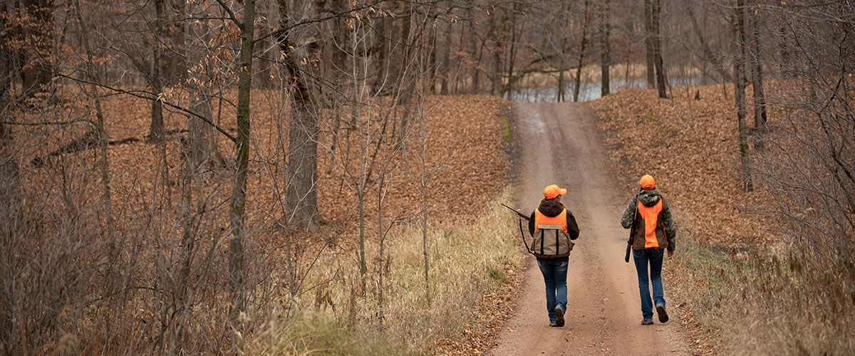 two hunters walking on a road