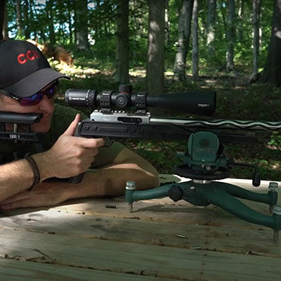 hunter aiming rifle in a wooded area