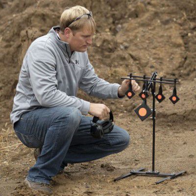 man kneeling beside some metal targets