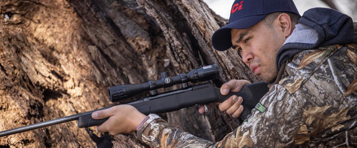 hunt aiming a rifle in the woods