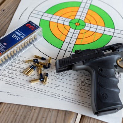 handgun with target, box of Subsonic and cartridges laying on a table