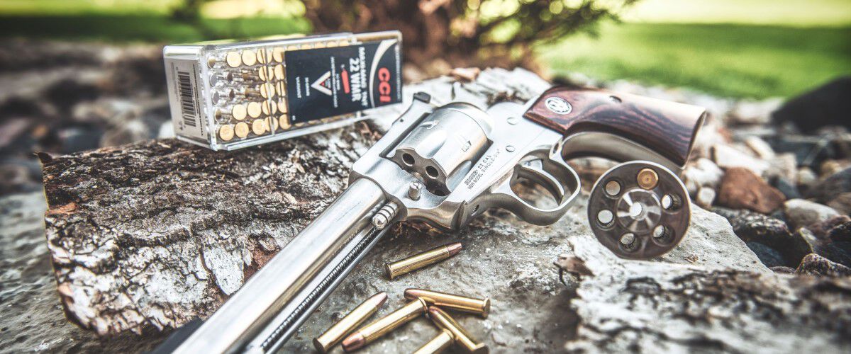 handgun laying on a tree stump with CCI ammo in the background