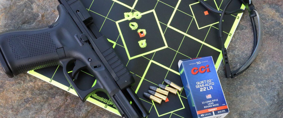 A handgun, glasses and CCI ammo laying on top of a shot target.
