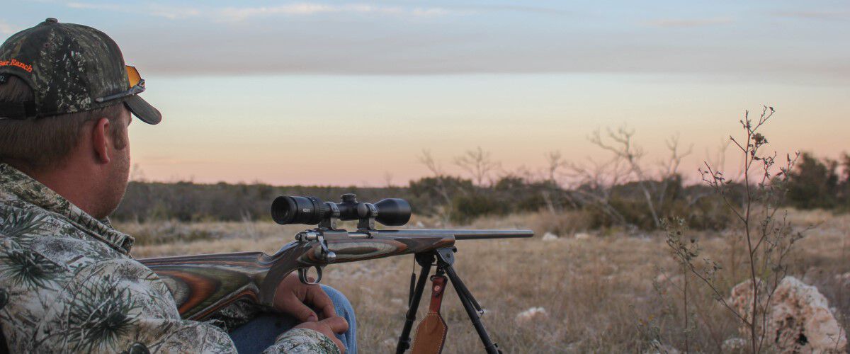hunter sitting beside a rifle outside