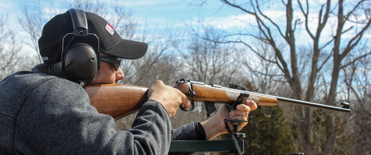 man looking down a rifle iron sights