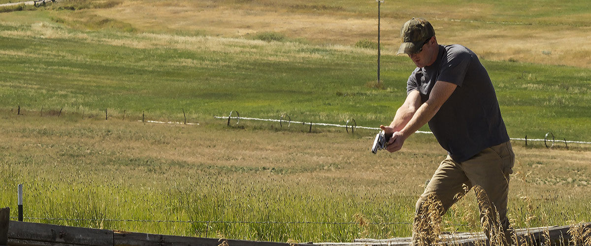 person aiming handgun while looking for pests outside