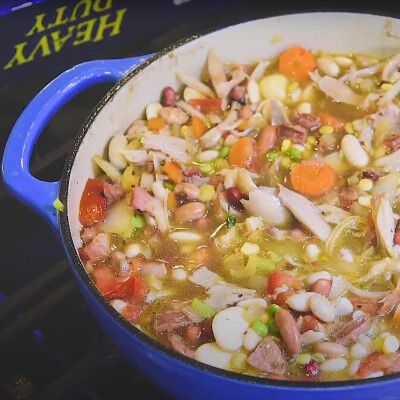 rustic bean cassoulet with rabbit confit in a blue cast iron dutch oven on a table