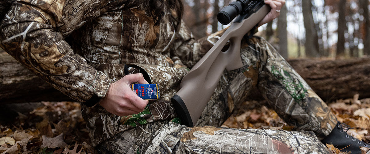 hunter pulling CCI ammo from a pocket while sitting in leaves on the ground