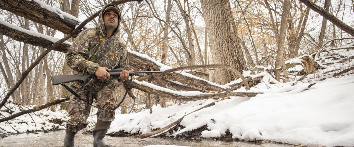 hunter carrying gun while walking in the snow